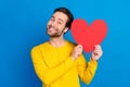 Portrait of attractive tender funny cheerful guy holding heart romance isolated over bright blue color background