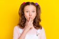 Portrait of attractive trendy amazed brown-haired girl showing shh sign taboo isolated over bright yellow color