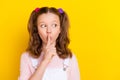 Portrait of attractive trendy brown-haired girl showing shh sign looking aside copy space isolated over bright yellow Royalty Free Stock Photo