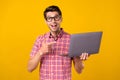 Portrait of attractive trendy cheerful guy geek using demonstrating laptop sign over bright yellow color