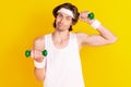 Portrait of attractive weak clueless sportive guy lifting weight isolated over bright yellow color background