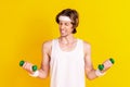 Portrait of attractive weak sportive guy lifting weight working out doing effort isolated over bright yellow color