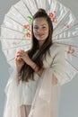 portrait of attractive woman in fashionable winter outfit standing with paper umbrella and looking at camera Royalty Free Stock Photo