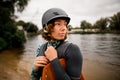 Portrait of attractive woman in helmet and vest who stands on the river bank Royalty Free Stock Photo