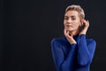 Portrait of attractive woman with pierced nose and short hair in blue turtleneck looking at camera, posing with hands Royalty Free Stock Photo