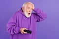 Portrait of attractive worried amazed man playing game pastime oops isolated over bright violet purple color background Royalty Free Stock Photo