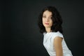 Portrait of attractive young adult girl with short dark curly hair looking at the camera in studio on black background Royalty Free Stock Photo