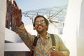 Portrait of attractive young African-American hipster in casual wear and sunglasses smiling and pointing hand.Blurred Royalty Free Stock Photo