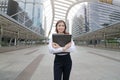 Portrait of attractive young Asian business woman holding document folder at sidewalk of urban city background. Royalty Free Stock Photo