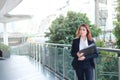 Portrait of attractive young Asian business woman holding document folder and walking in office. Royalty Free Stock Photo