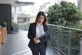 Portrait of attractive young Asian business woman holding document folder and walking in office. Royalty Free Stock Photo