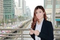 Portrait of attractive young Asian business woman holding mobile smart phone and smiling at urban building city with copy space ba Royalty Free Stock Photo