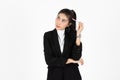 Portrait of attractive young Asian business woman holding pen and having idea posing over white isolated background Royalty Free Stock Photo