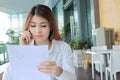 Portrait of attractive young Asian business woman talking on phone against holding document files on her hand in office. Royalty Free Stock Photo