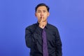 Portrait of attractive young asian man making silence gesture on purple background Royalty Free Stock Photo