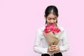 Portrait of attractive young Asian woman holding a bouquet of red roses on pink isolated background. Valentine`s day concept. Royalty Free Stock Photo