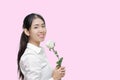 Portrait of attractive young Asian woman holding white rose on pink isolated background. Valentines day concept. Royalty Free Stock Photo