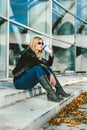 Portrait of attractive young caucasian blonde woman sitting with cup of coffee in front of business building Royalty Free Stock Photo