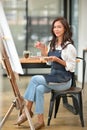 Portrait of attractive young female holding palette colour, large canvas easel