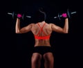 Portrait of an attractive young fitness woman in sportswear doing workout with dumbbells on black background. Royalty Free Stock Photo