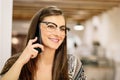 Portrait of an attractive young girl with glasses talking on the phone while working from a bar. Telecommuting Royalty Free Stock Photo