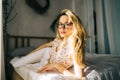 Portrait of attractive young happy caucasian woman in glasses, sitting in cozy bedroom Royalty Free Stock Photo