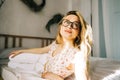 Portrait of attractive young happy caucasian woman in glasses, sitting in cozy bedroom Royalty Free Stock Photo