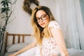 Portrait of attractive young happy caucasian woman in glasses, sitting in cozy bedroom Royalty Free Stock Photo