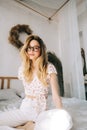 Portrait of attractive young happy caucasian woman in glasses, sitting in cozy bedroom Royalty Free Stock Photo