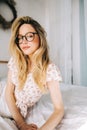 Portrait of attractive young happy caucasian woman in glasses, sitting in cozy bedroom Royalty Free Stock Photo