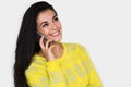 Portrait of attractive young happy woman with smart phone, wearing yellow sweater, with pretty toothy smile, on the white wall Royalty Free Stock Photo