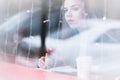 Portrait of an attractive young journalist girl with pen and notepad in cafe behind the showcase. Non-contrast view