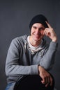 Portrait of an attractive young male model in black hat, jeans and gray sweatshirt, studio, dark gray background Royalty Free Stock Photo