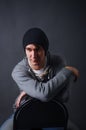 Portrait of an attractive young male model in black hat, jeans and gray sweatshirt, studio, dark gray background Royalty Free Stock Photo
