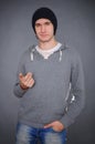 Portrait of an attractive young male model in black hat, jeans and gray sweatshirt, studio, dark gray background Royalty Free Stock Photo