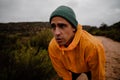 Portrait attractive young male runner resting after fast downhill sprint on mountain trail in cloudy weather with Royalty Free Stock Photo