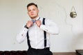 Attractive young man, future generation businessman stand near sofa and hold him bow tie