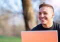 Portrait of attractive young office worker in casual wear, smiling in a break moment. He works remotely with the laptop from a Royalty Free Stock Photo