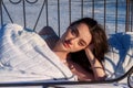 Portrait of an attractive, young, sexy, seductive dark brown haired woman in Bed, in white nightwear, head on hand, outside in Royalty Free Stock Photo