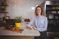 Portrait of attractive young waitress using digital tablet while standing by counter Royalty Free Stock Photo