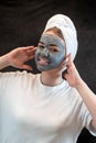 Portrait of attractive young woman apply clay mud mask on her face isolated on black Royalty Free Stock Photo