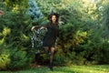 Portrait of an attractive young woman in a black dress with a cape on a background of green forest Royalty Free Stock Photo