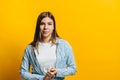 Portrait of attractive young woman with brunette hair and crossed arms looking on camera. isolated on yellow background, studio Royalty Free Stock Photo