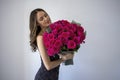 Portrait of an attractive young woman dressed in red dress holding bouquet of roses isolated over white background Royalty Free Stock Photo