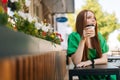 Portrait of attractive young woman enjoying tasty cup of coffee sitting at table in outdoor cafe terrace in summer day. Royalty Free Stock Photo