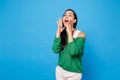 Portrait of attractive young woman in green casual clothes looking aside, screaming with hands near mouth isolated on Royalty Free Stock Photo