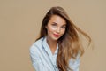 Portrait of attractive young woman has fair hair floating in wind, natural beauty, wears makeup, dressed in stylish shirt, Royalty Free Stock Photo