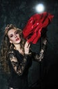 Portrait of an attractive young woman in a long black dress with a very big rose on a grunge wall background Royalty Free Stock Photo