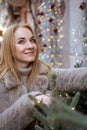 Portrait of attractive young woman near the Christmas decorations standing outdoors. Christmas mood, holidays. Vertical frame Royalty Free Stock Photo