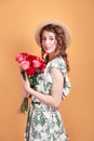 Portrait of attractive young woman in summer dress and straw hat holding roses bouquet on yellow background Royalty Free Stock Photo